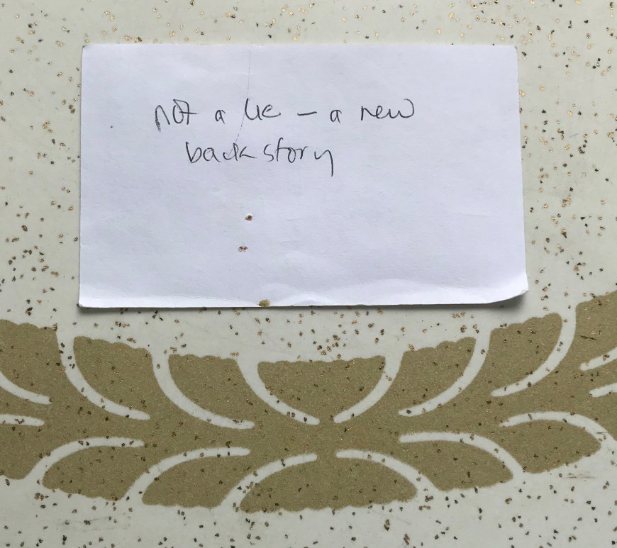 The comment "not a lie - a new backstory" written onto an unlined 5x7 note card.